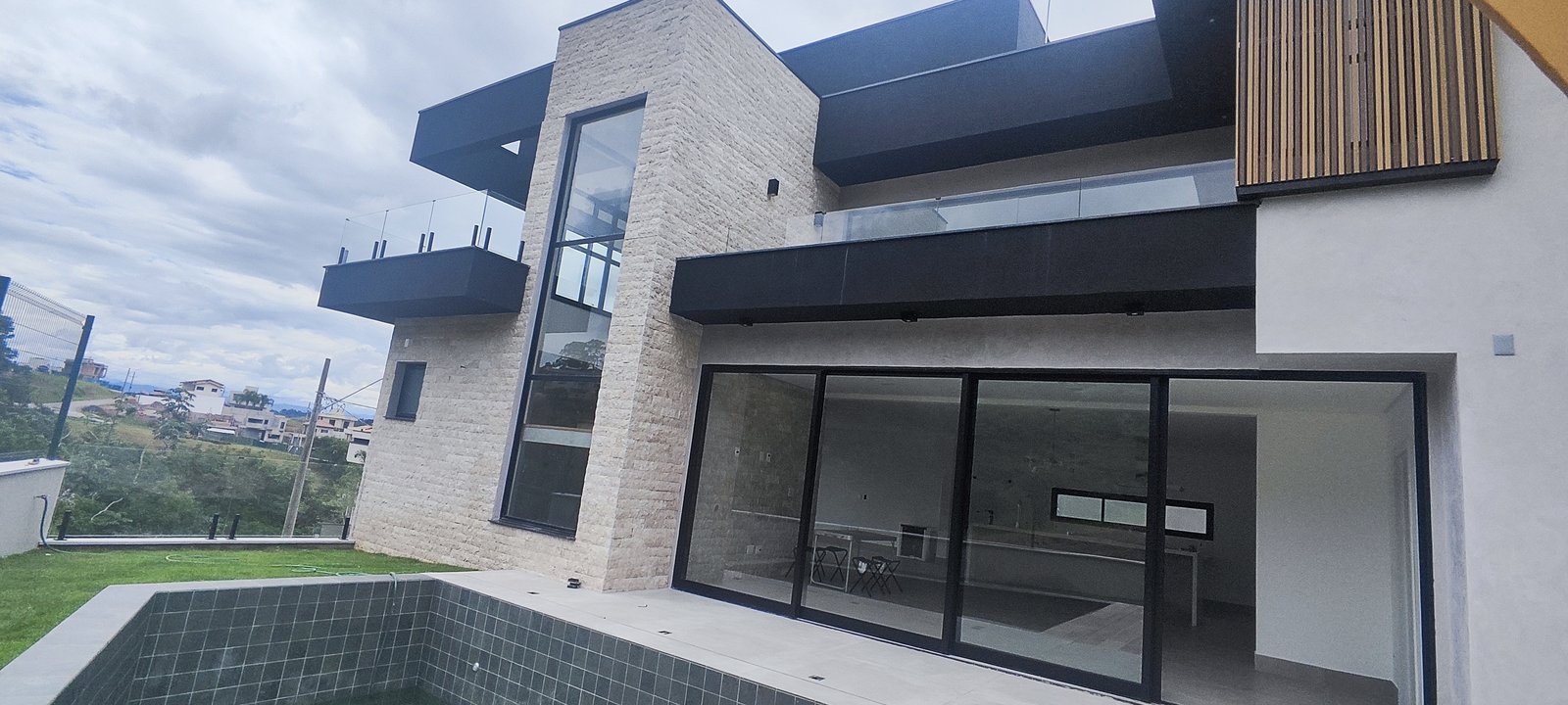 Casa concluída pela GMF Engenharia, com piscina, fachada em pedra clara e grandes portas de vidro
